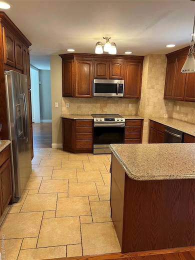 Kitchen with stainless steel range, tasteful backsplash, recessed lighting, refrigerator, and light stone countertops