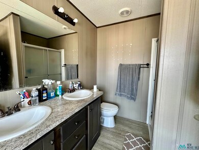Bathroom with ornamental molding, a shower stall, a textured ceiling, light wood-style flooring, and double vanity