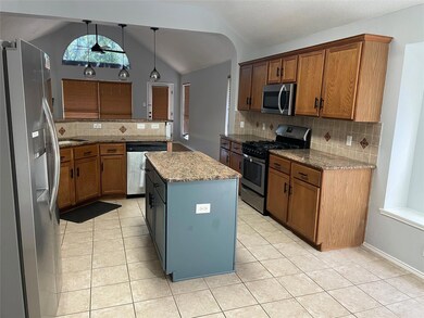 Kitchen with appliances with stainless steel finishes, decorative light fixtures, light stone countertops, and tasteful backsplash