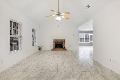 Unfurnished living room featuring ceiling fan, a fireplace, light marble finish floors, and a chandelier