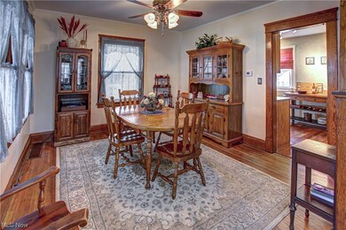 Dining area with ceiling fan, dark wood-type flooring, and crown molding