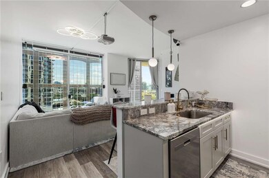 Kitchen with dishwasher, wood finished floors, stone countertops, open floor plan, and a breakfast bar area