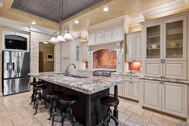 Kitchen with a raised ceiling, stone tile floors, appliances with stainless steel finishes, ornamental molding, and arched walkways