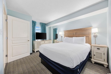 Bedroom featuring dark carpet and a textured ceili