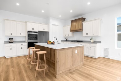 Kitchen featuring a kitchen island with sink, recessed lighting, appliances with stainless steel finishes, a breakfast bar, and light wood finished floors