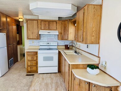 Kitchen with decorative backsplash, white appliances, and brown cabinetry