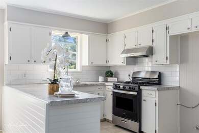 Kitchen with stainless steel gas stove, white cabi
