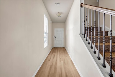 Corridor with light wood-style floors and baseboar
