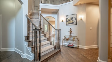 Staircase featuring wood finished floors, arched walkways, and a high ceiling