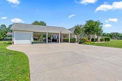 View of front of property with a front lawn, a carport, driveway, a garage, and a shingled roof