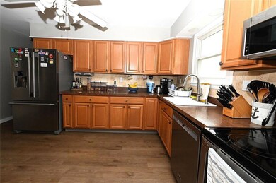 Kitchen with appliances with stainless steel finishes, ceiling fan, tasteful backsplash, wood finished floors, and dark countertops