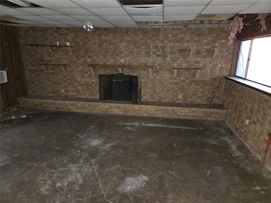 Basement featuring a drop ceiling and a brick fireplace