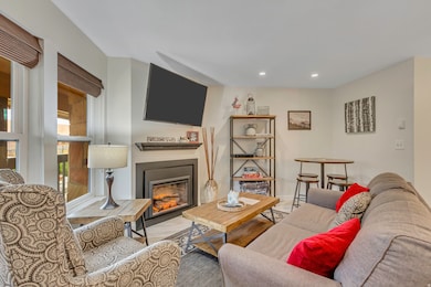 Living room with a glass covered fireplace, wood finished floors, and recessed lighting