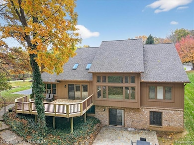 Back of house featuring a wooden deck, a shingled roof, and brick siding