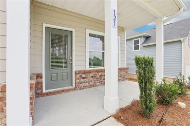 Doorway to property featuring covered porch, brick siding, and roof with shingles