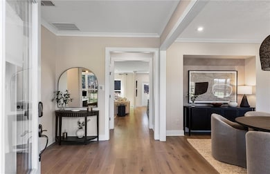Entryway with wood finished floors and crown molding