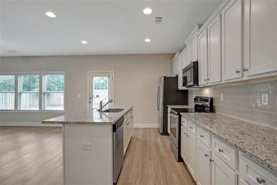 Kitchen with white cabinetry, an island with sink,