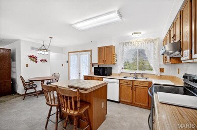Kitchen with electric range oven, a kitchen island, dishwasher, light countertops, and a breakfast bar area