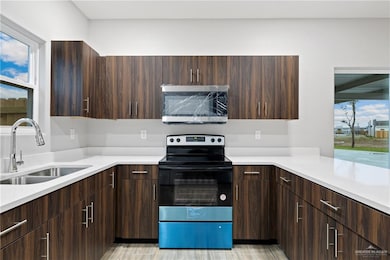 Kitchen with appliances with stainless steel finishes, dark brown cabinets, plenty of natural light, and sink