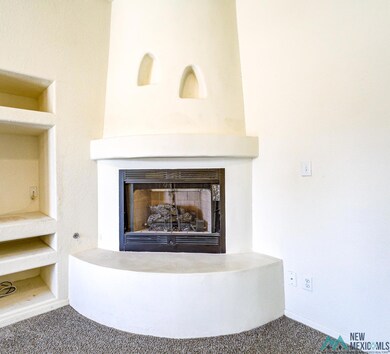 Detailed view of a fireplace with raised hearth, built in features, and carpet flooring