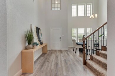 Foyer entrance with a chandelier, light hardwood / wood-style flooring, and a towering ceiling