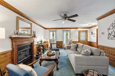 Carpeted living room featuring ceiling fan and orn