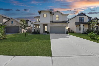 This modern two-story home features a sleek design with a spacious driveway and a neatly manicured front lawn. It includes a double garage, and the exterior combines light brick with dark roof accents. The sky at dusk adds a warm, inviting atmosphere.