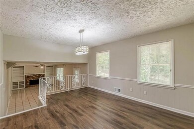 Unfurnished dining area featuring a textured ceiling, a fireplace, plenty of natural light, a wainscoted wall, and dark wood-type flooring