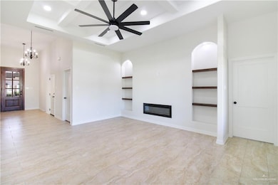 Unfurnished living room featuring beam ceiling, coffered ceiling, a glass covered fireplace, a chandelier, and recessed lighting