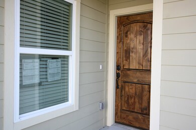Nice stained wood front door is under small covered porch to keep the rain off.
