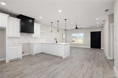 Kitchen featuring ceiling fan, kitchen peninsula, tasteful backsplash and white cabinets