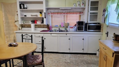 Kitchen with backsplash, white cabinetry, sink, an