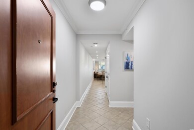 Hall featuring ornamental molding and light tile p