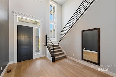 Entrance foyer with light wood-style flooring, stairway, and a high ceiling