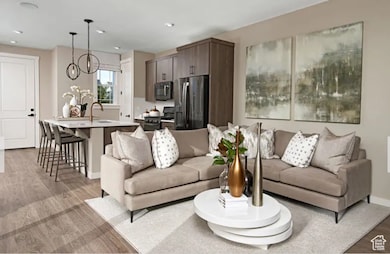 Living room featuring light wood finished floors, a chandelier, and recessed lighting