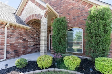 Doorway to property featuring brick siding and a shingled roof