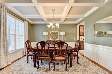 Dining room with beam ceiling, a chandelier, a decorative wall, a wainscoted wall, and coffered ceiling