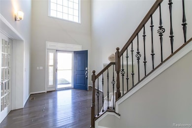 Foyer with a high ceiling, dark wood-style floors, and stairway