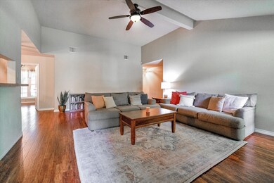 Huge living room with vaulted ceiling, gleaming floors, and a wood burning fireplace.