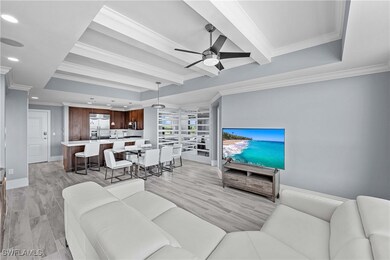 Living room featuring crown molding, light hardwood / wood-style floors, beamed ceiling, sink, and ceiling fan