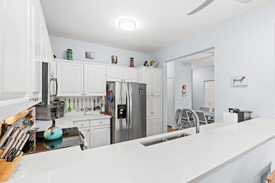 Kitchen with stainless steel fridge with ice dispenser, a sink, light countertops, backsplash, and white cabinetry