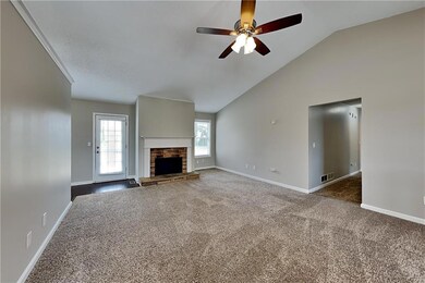 Unfurnished living room featuring dark carpet, a stone fireplace, ceiling fan, and vaulted ceiling