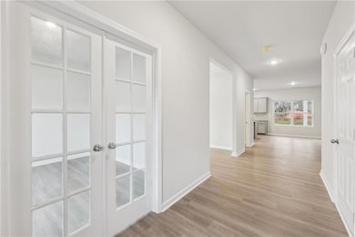 Corridor featuring light wood finished floors, bas