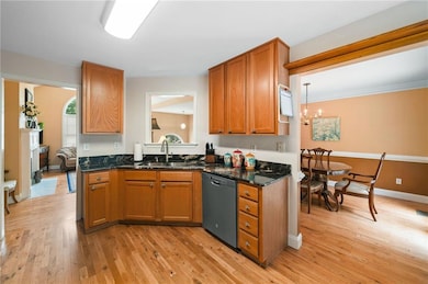Kitchen featuring dishwasher, light wood-type flooring, brown cabinets, and a chandelier