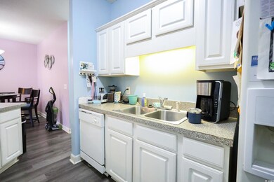 Kitchen with dark wood-type flooring, white dishwa