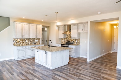 Kitchen with decorative backsplash, pendant lighting, stainless steel range with electric cooktop, light stone countertops, and recessed lighting