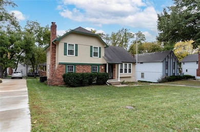 View of front of house with brick siding, a chimney, a front yard, and stucco siding
