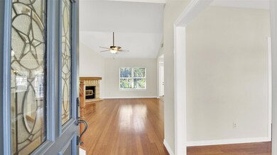 Foyer entrance with light wood finished floors, lofted ceiling, a fireplace, and a ceiling fan
