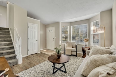 Living room with wood finished floors, a textured ceiling, and stairs
