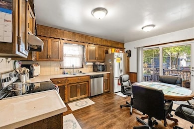Kitchen featuring decorative backsplash, brown cabinets, dark wood-style floors, stainless steel appliances, and plenty of natural light